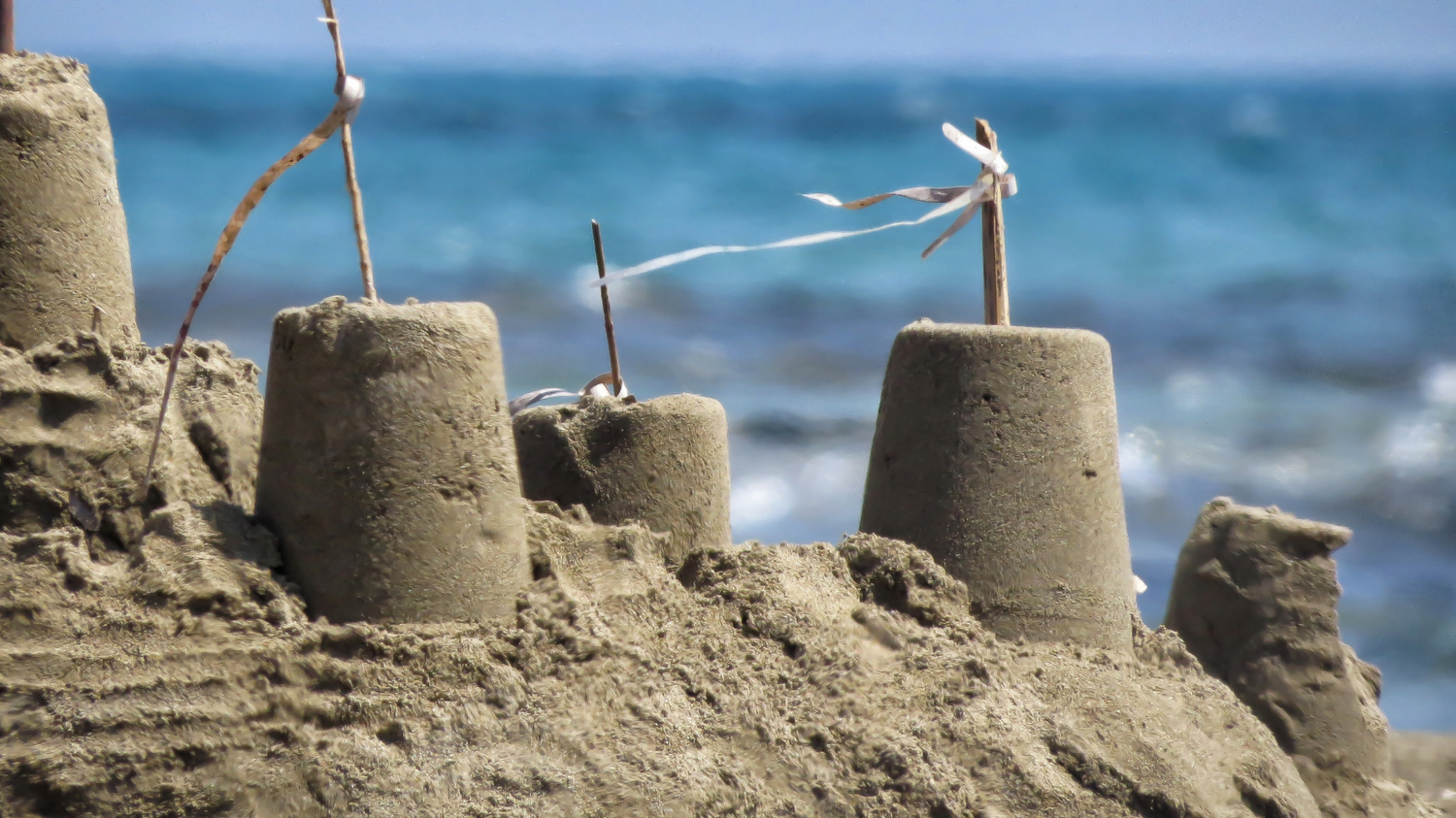 Sandcastles with stick flags on a beach